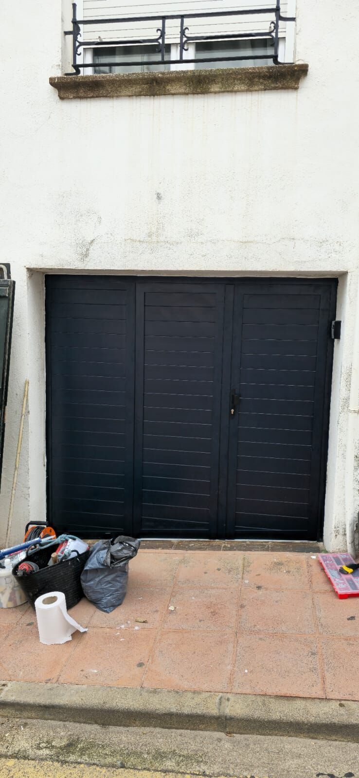 Puerta de aluminio negra de dos hojas en una fachada blanca