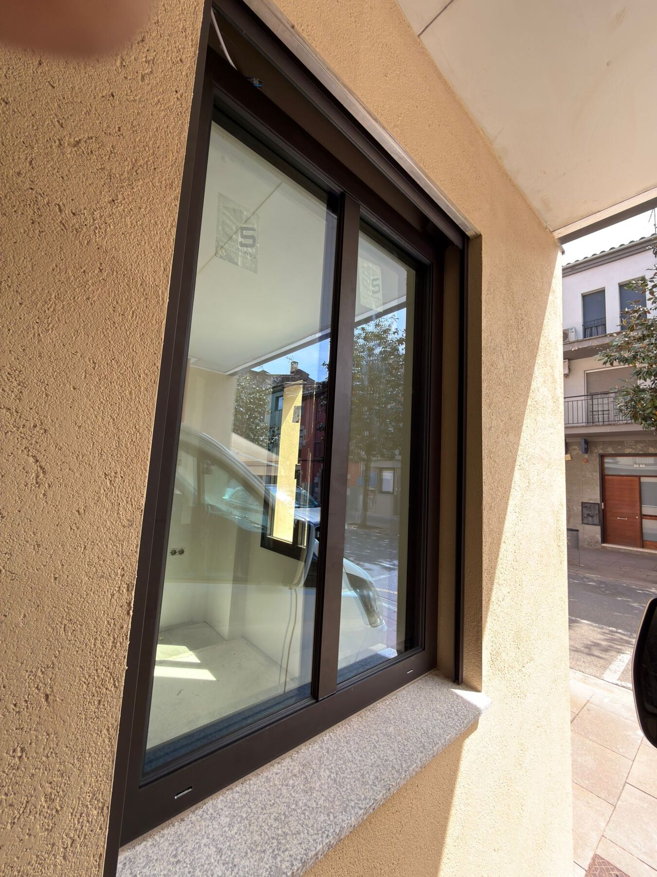 Ventana corredera de aluminio oscura vista en ángulo desde la calle